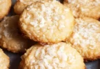 Delicious chewy coconut cookies on a wooden surface