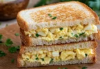 Delicious Egg Mayo Sandwich on a plate, garnished with herbs.