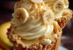 Banana pudding cheesecake cones topped with whipped cream and banana slices