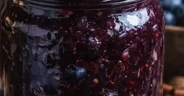 Jar of homemade blueberry butter spread on toast.