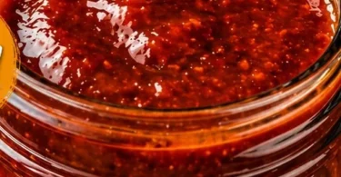 Bottle of Bourbon Peach BBQ Sauce drizzled over grilled meat