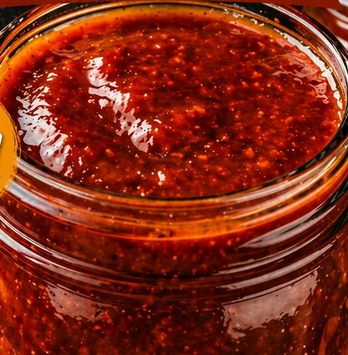 Bottle of Bourbon Peach BBQ Sauce drizzled over grilled meat