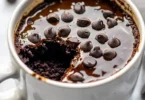 Delicious chocolate protein mug cake topped with chocolate chips in a mug.