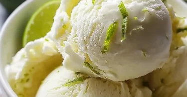 Creamy Coconut Lime Ice Cream in a bowl topped with lime zest and coconut flakes.