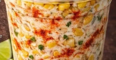 Creamy Mexican street corn cup topped with cheese and herbs