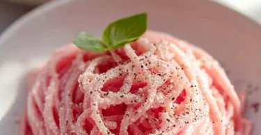 Creamy vegan pink pasta dish topped with fresh herbs and vegetables.