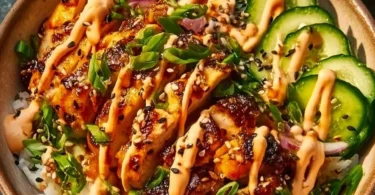 Crispy chicken with spicy sauce served over jasmine rice in a bowl.