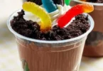 Delicious and fun dirt cups dessert with chocolate, gummy worms, and crushed cookies.