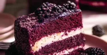 Slice of dreamy blackberry velvet cake topped with fresh blackberries