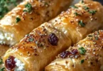 Golden baked feta rolls drizzled with sweet cranberry honey on a plate
