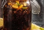 A glass of homemade Coca Cola with ice and a slice of lemon