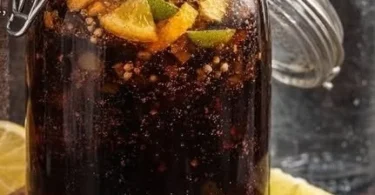 A glass of homemade Coca Cola with ice and a slice of lemon