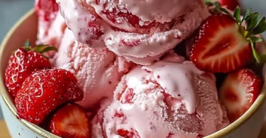 Bowl of homemade strawberry ice cream topped with fresh strawberries and mint leaves