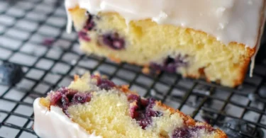 Lemon blueberry sheet cake topped with fresh blueberries and lemon zest garnish