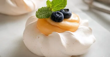 Meringues topped with vibrant citrus curd on a stylish dessert plate.