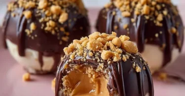 No-bake peanut butter cheesecake balls with chocolate drizzle on a plate.