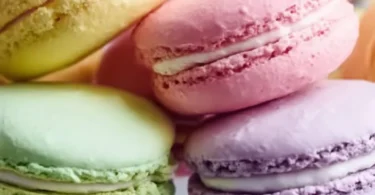Pastel sugar cookie sandwiches with creamy filling on a plate
