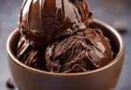 Rich homemade chocolate ice cream in a bowl with chocolate shavings on top.