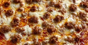 A slice of school pizza with cheese and toppings served on a plate.