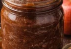 Jar of slow-cooked spiced apple butter with apples and spices