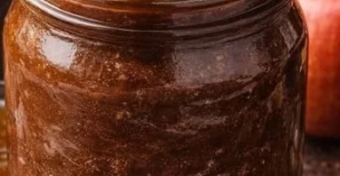 Jar of slow-cooked spiced apple butter with apples and spices