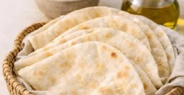 Soft and puffy Arabic bread (Kuboos) on a wooden table, showcasing its texture.