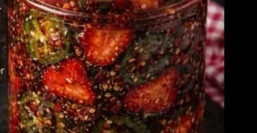 Strawberry jalapeño cowboy candy in a jar showcasing its vibrant colors.