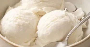 Delicious tender coconut ice cream in a bowl topped with coconut flakes.