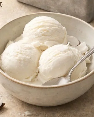 Delicious tender coconut ice cream in a bowl topped with coconut flakes.