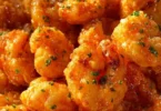 A plate of crispy Bang Bang Shrimp garnished with green onions and spicy sauce.