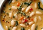A bowl of nutritious high protein white bean soup topped with herbs.