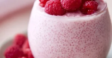 Vanilla raspberry chia pudding in a glass bowl topped with fresh raspberries