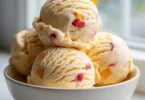 Bowl of homemade peach ice cream with fresh peaches and cream