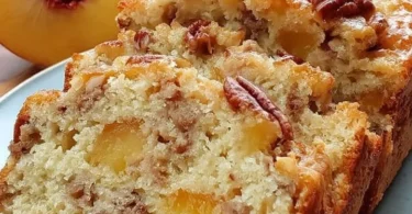 Loaf of homemade Peach Pecan Bread with fresh peaches and pecans