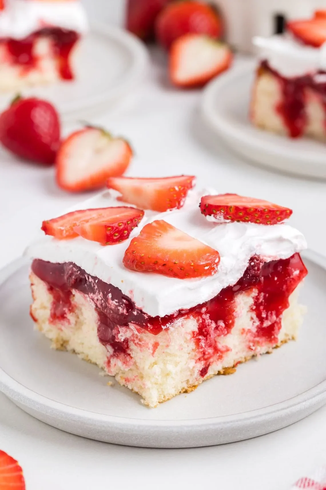 Delicious strawberry shortcake poke cake topped with fresh strawberries and whipped cream.