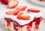 Delicious strawberry shortcake poke cake topped with fresh strawberries and whipped cream.