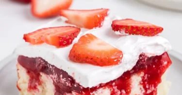 Delicious strawberry shortcake poke cake topped with fresh strawberries and whipped cream.